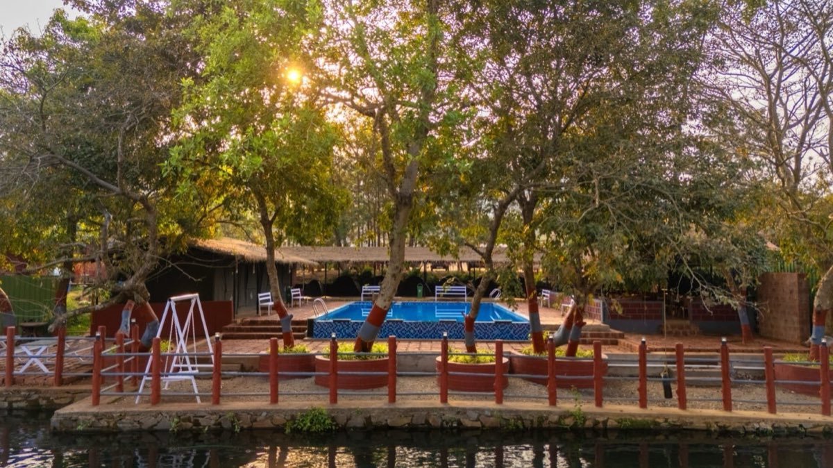 Nadi Teera pool and thatched pavilion seen across the river at golden hour